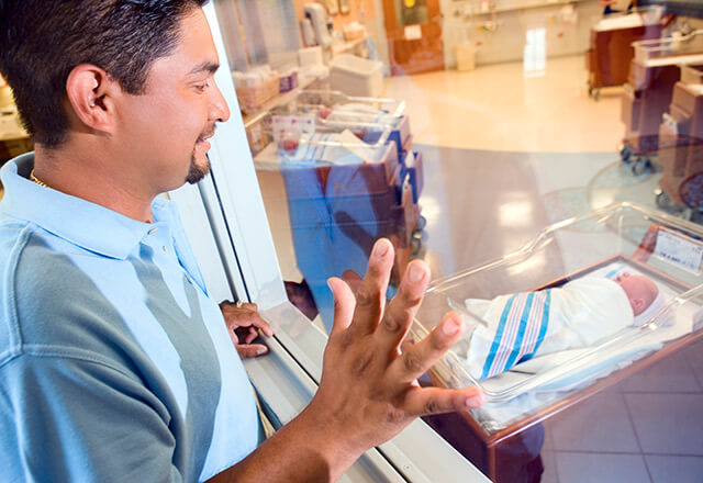 a father looks in on his newborn baby