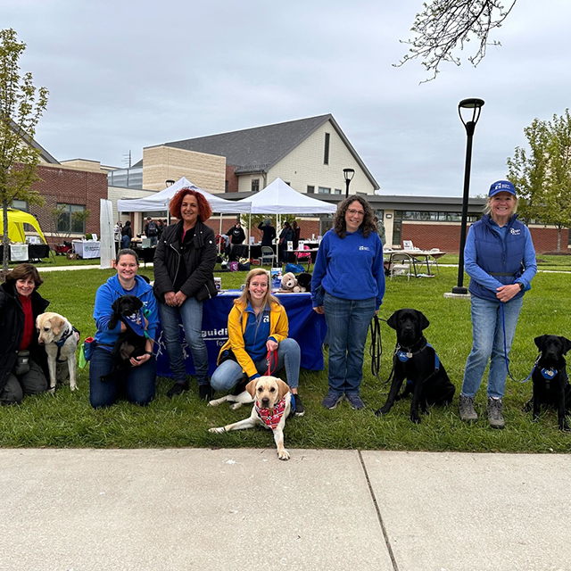 Nurses smiling and posing with guide dogs on a lawn