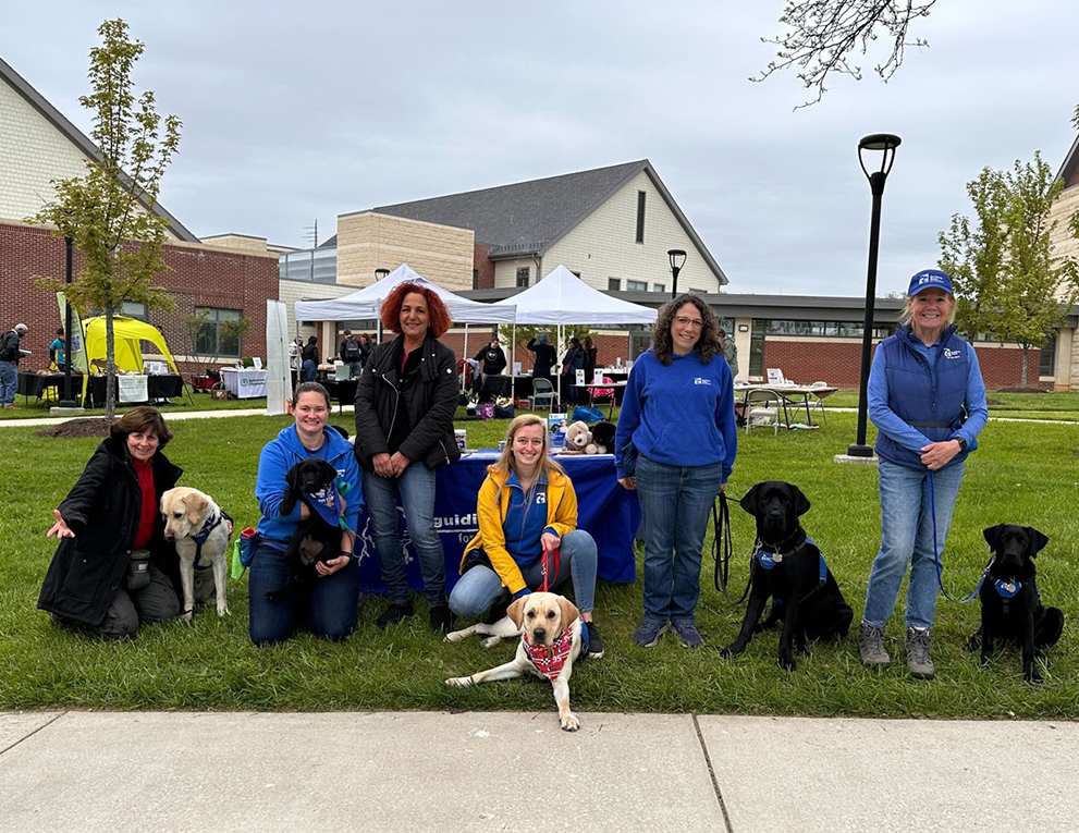 Nurses posing with guide dogs on a lawn