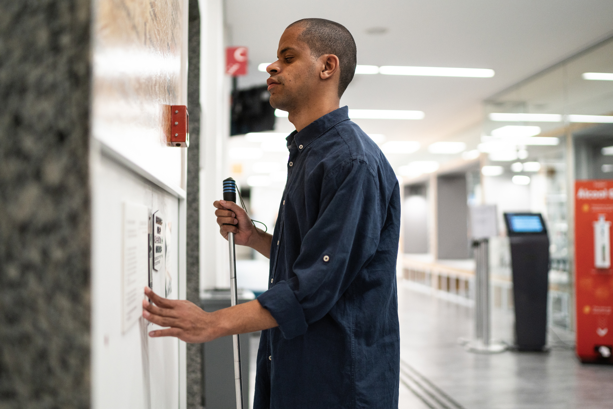 A middle-aged man with vision loss waiting for an elevator