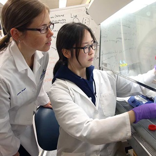 Two researchers in white coats working in the lab