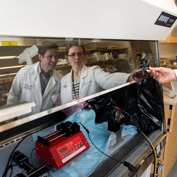 Justin and Laura reflected onto the glossy surface of lab equipment
