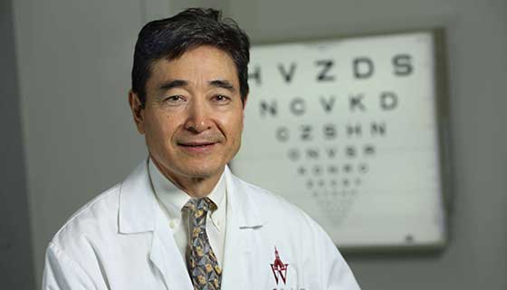 Doctor Handa standing in front of a Snellen chart