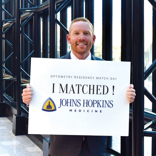 Doctor Salus holding a sign that reads I matched Johns Hopkins Medicine
