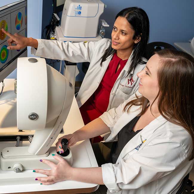 Two physicians examine a computer monitor