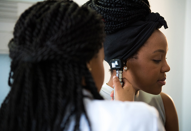 Doctor examining a female patients ear. 
