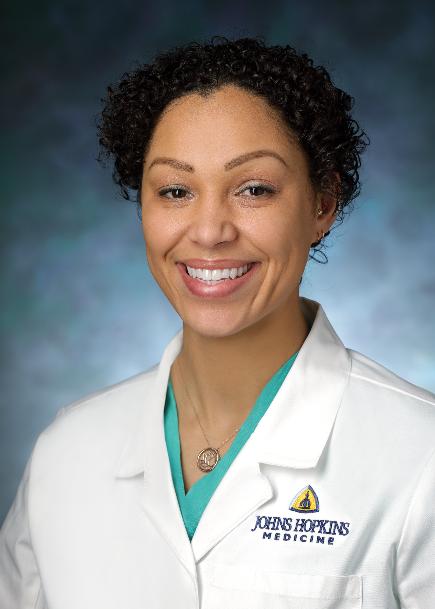 Carly Campbell smiles for a professional photo in her white coat.
