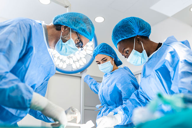 Three doctors in masks and gowns with surgical equipment