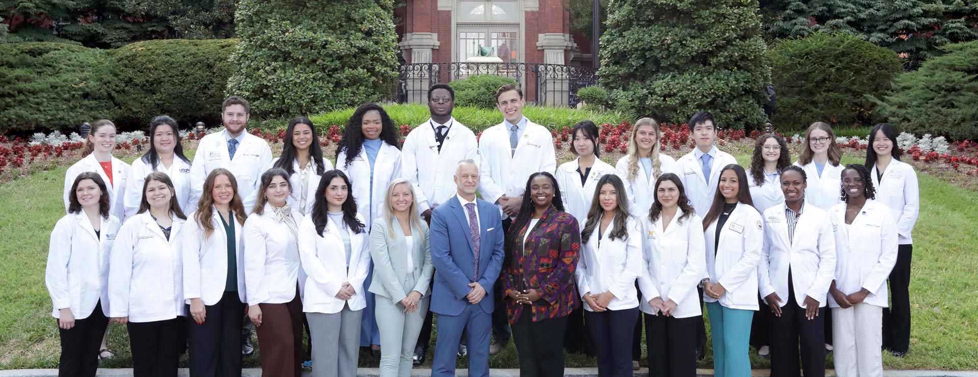 The 2026 class of pharmacy interns pose with program staff for a group photo in front of the original Johns Hopkins building in east Baltimore. 