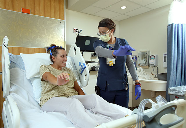 A clinician helping a patient in a hospital bed practice safe mobility.