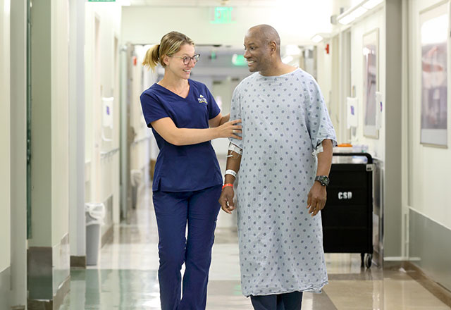 woman helping a patient walk in the hallway