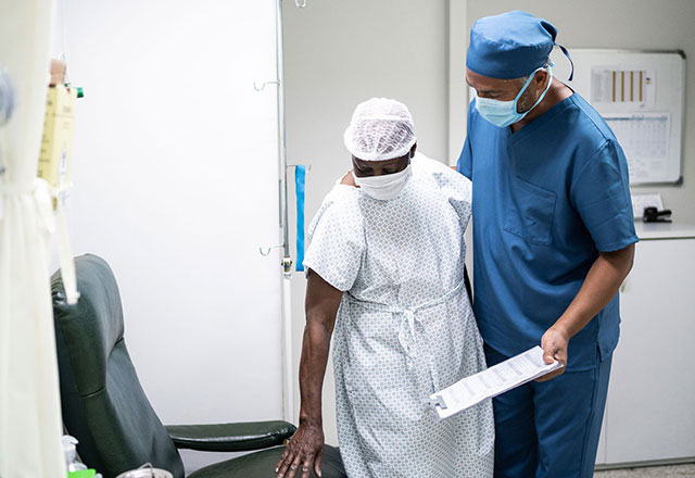a clinician helps a patient out of a chair