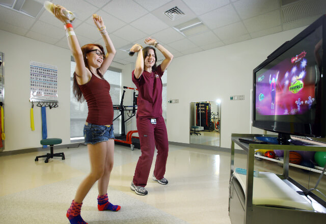 Physical therapist playing active video game with patient.