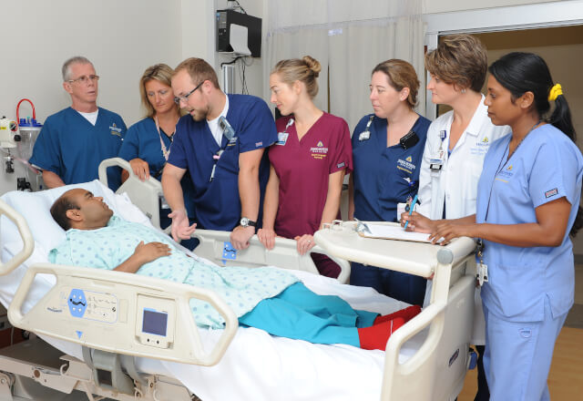 A clinical team gathered around a patient who had tracheostomy