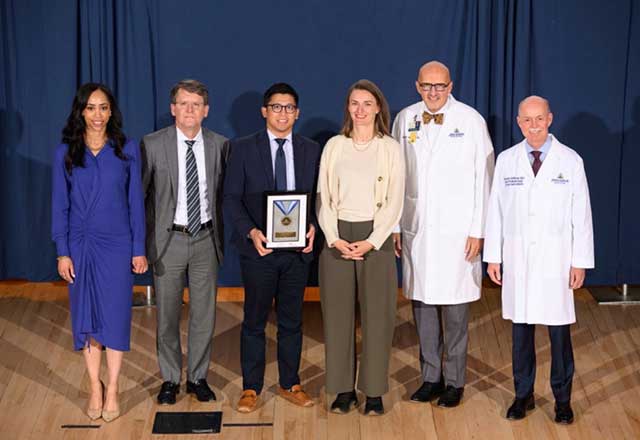 Dr. Chua standing and holding the award alongside Dr. Keatley and other award presenters.