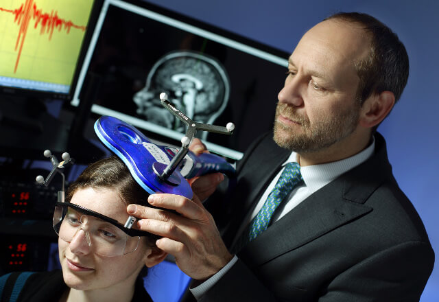 Dr. Celnik places a NIBS device on a patient's head