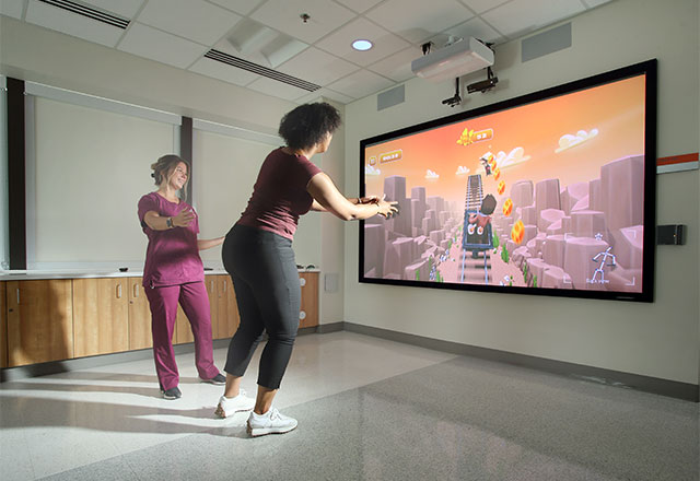 A patient using our immersive gaming technology with a therapist monitoring.