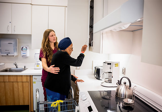 A patient folding clothing with a therapist in a mock apartment room.