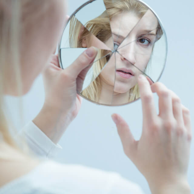 girl looking through shattered mirror