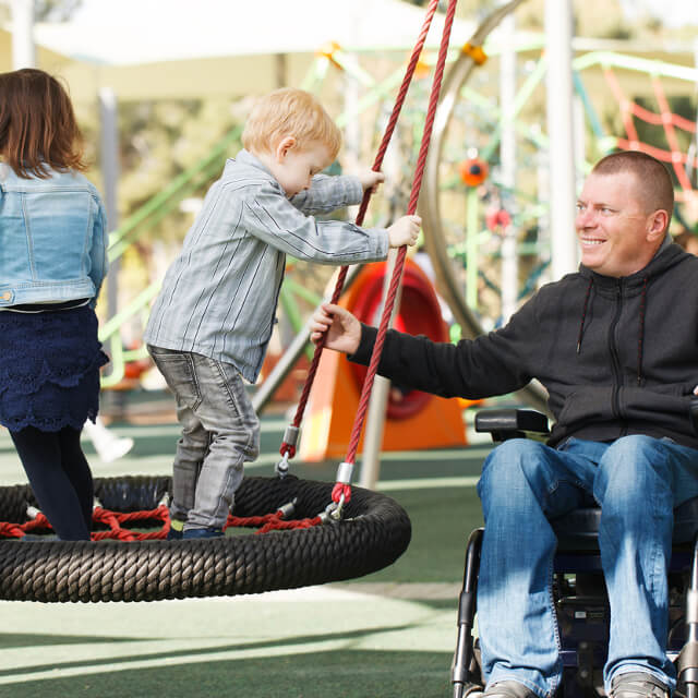 A man in a wheelchair playing with children