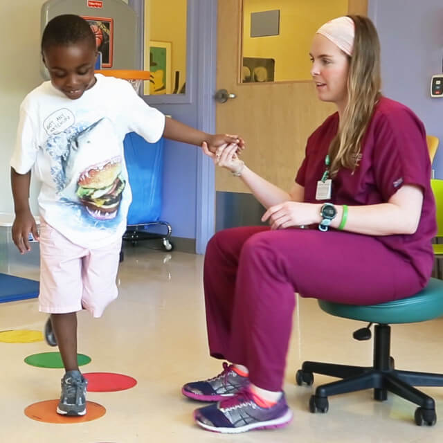 Pediatric occupational therapist helping a child jump