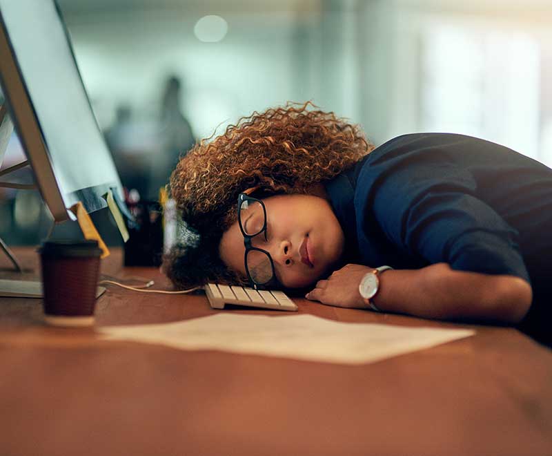 a woman sleeping on her desk at work