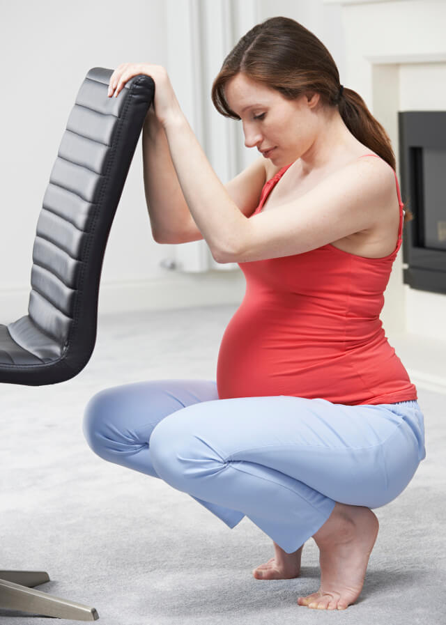 A pregnant woman stretching on a chair