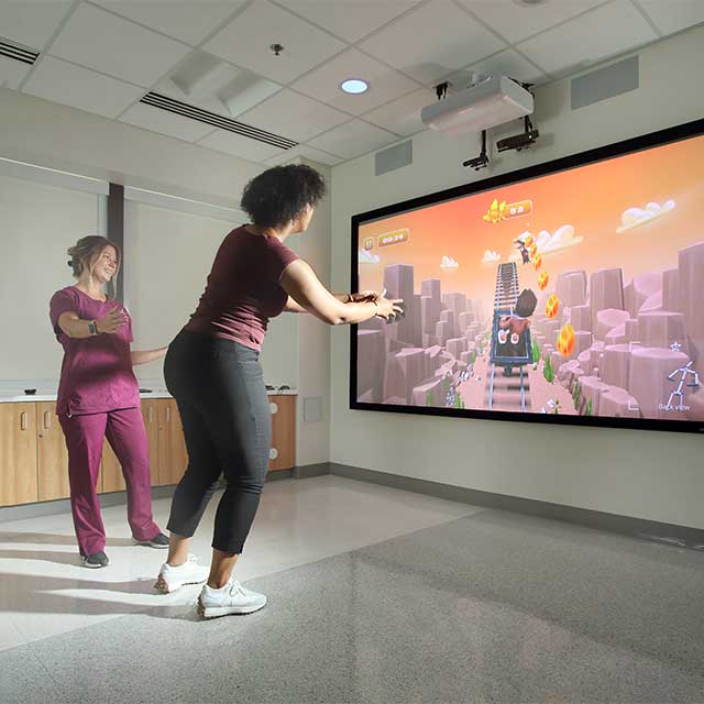 Therapist working with a patient using a game simulation device.