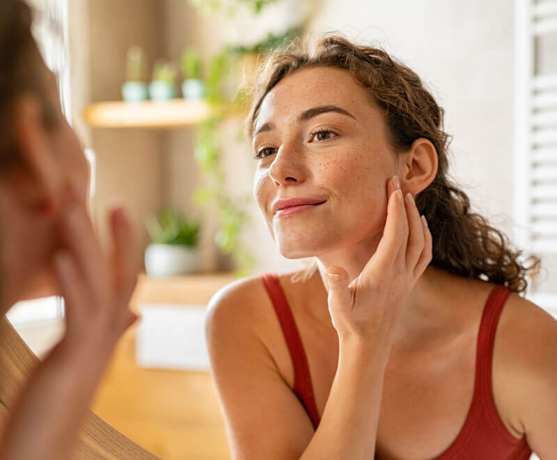 Woman happily looking in mirror.