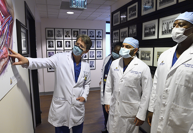 Dr. Redett and two other physicians discussing a chart on the wall.