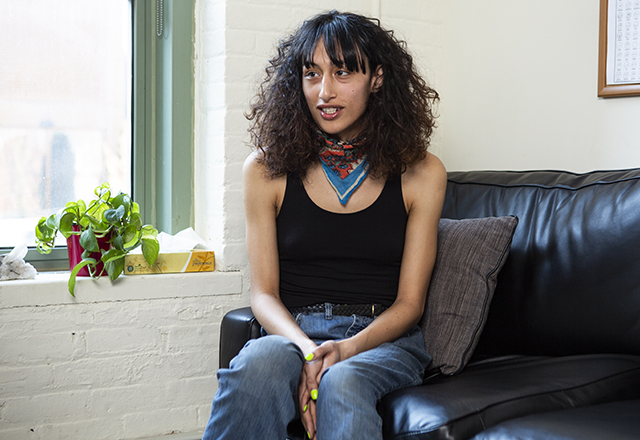 A transgender woman sits on a couch.