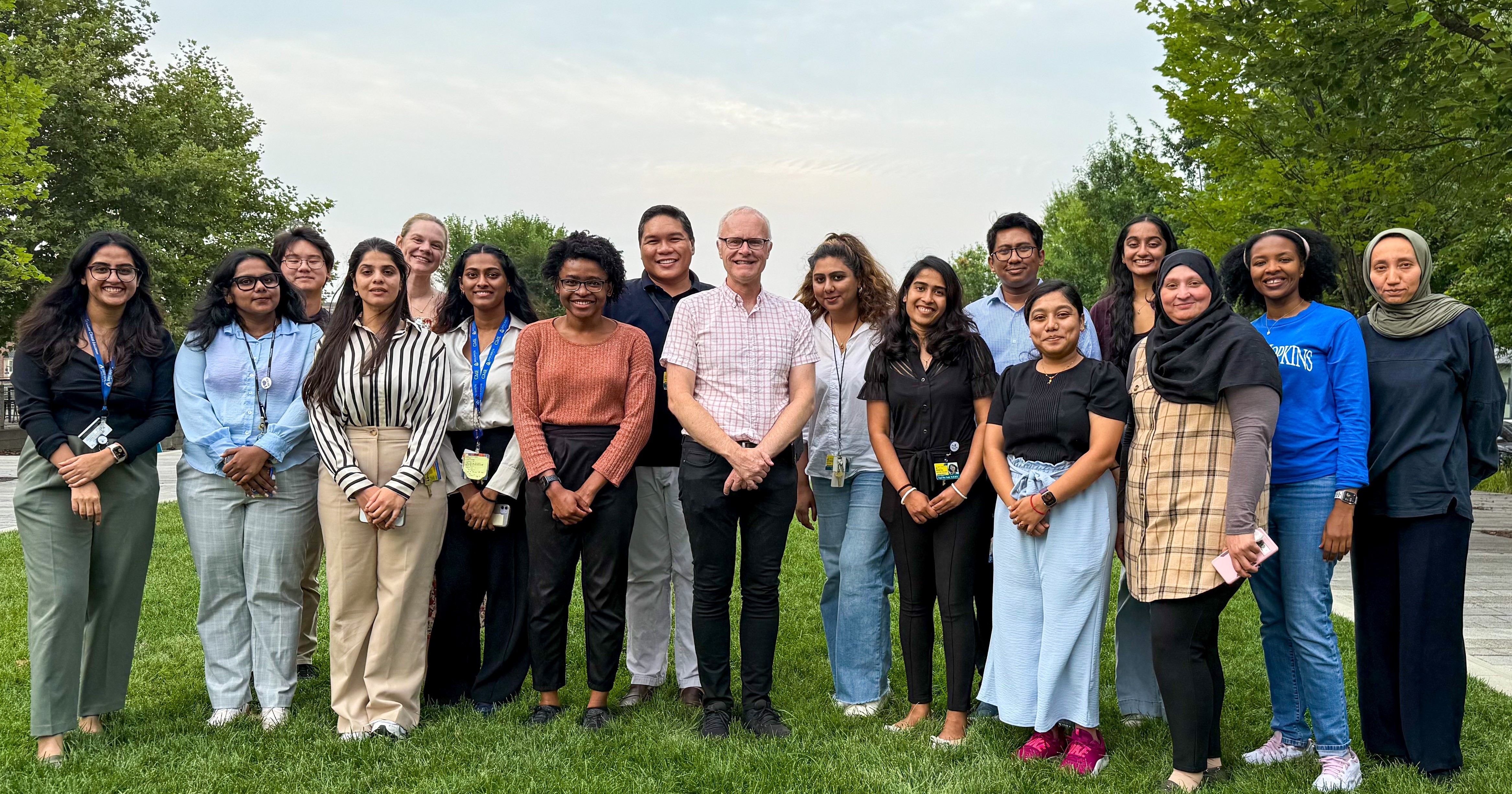 OACIS Group (17 people) 2025 on green grass surrounded by trees
