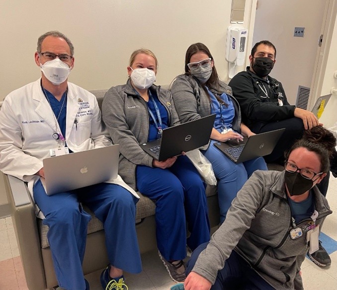 Doctors holding laptops with masks on smiling