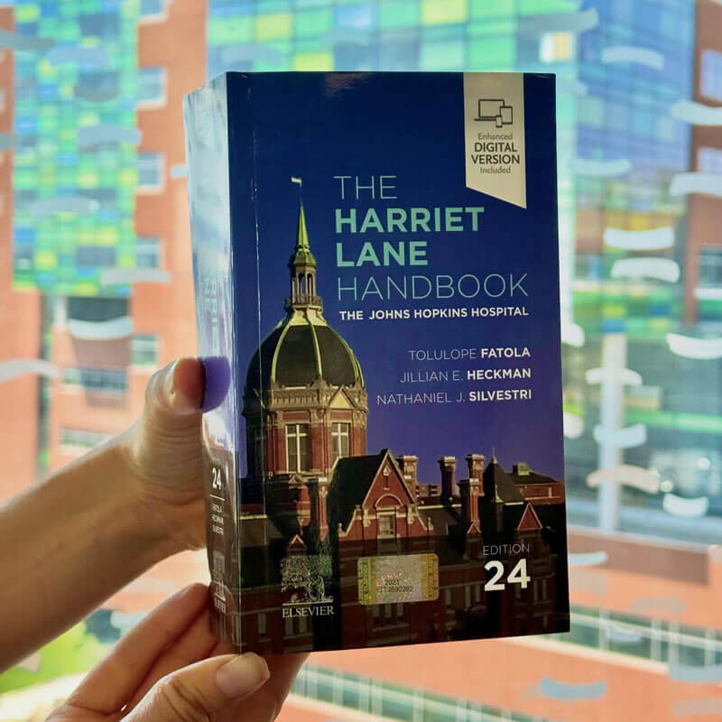 Hands holding a copy of the 24th edition of the Harriet Lane Handbook