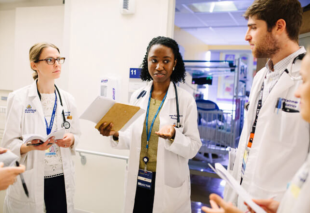 group of residents at the standing outside of a patient room and consulting 