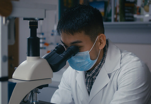 man researches with microscope
