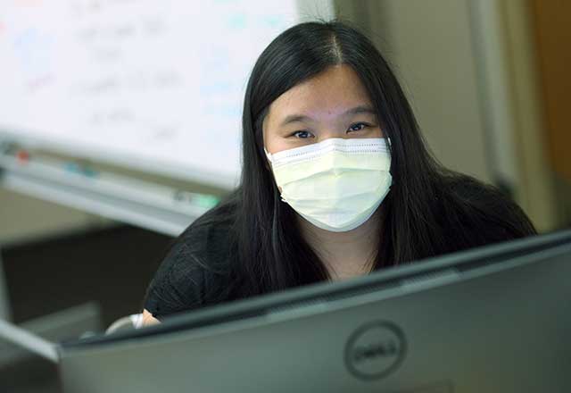 Employee wearing a mask and looking at a computer.