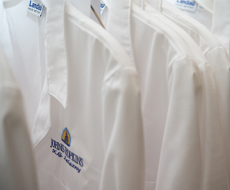 A collection of white coats on hangers.