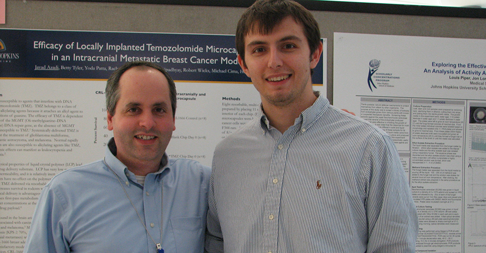 Two researchers pose in front of a poster.