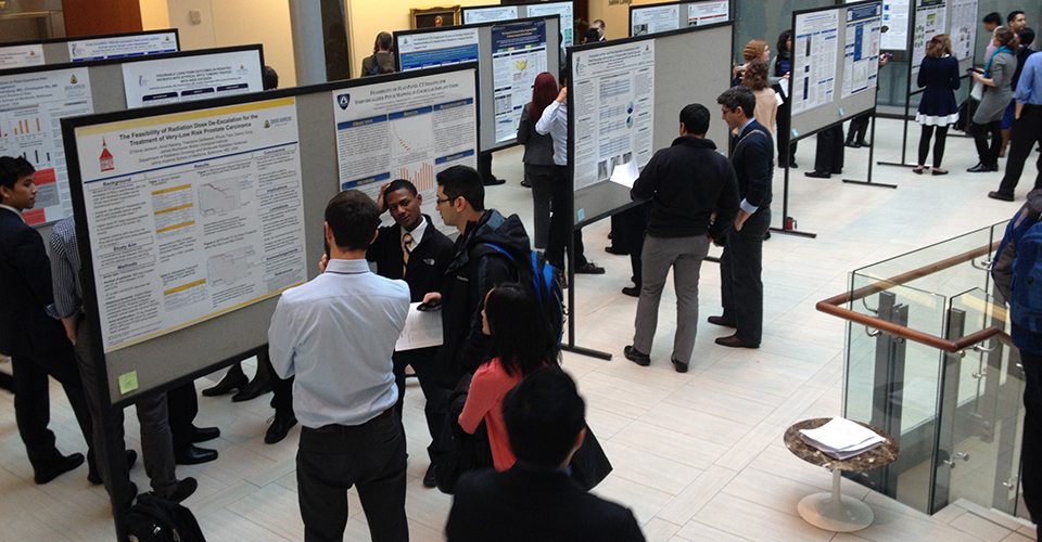 A group of attendees browse research posters.