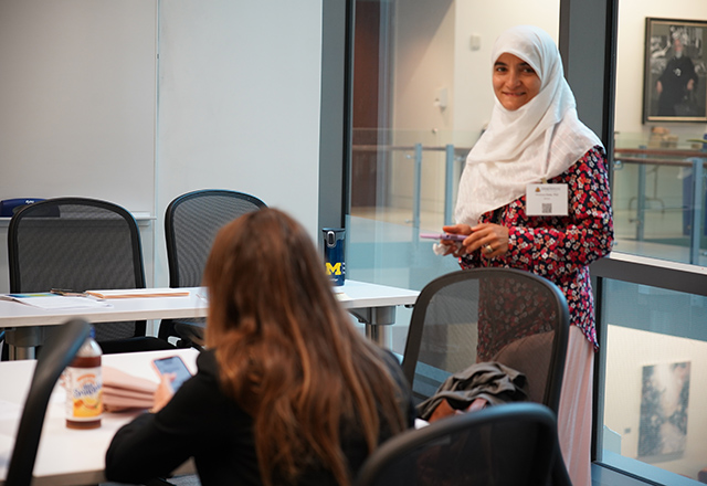 A faculty member stands, smiling at the camera.