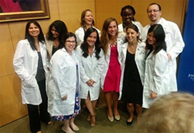 Graduate students pose together happily after receiving their white coats.