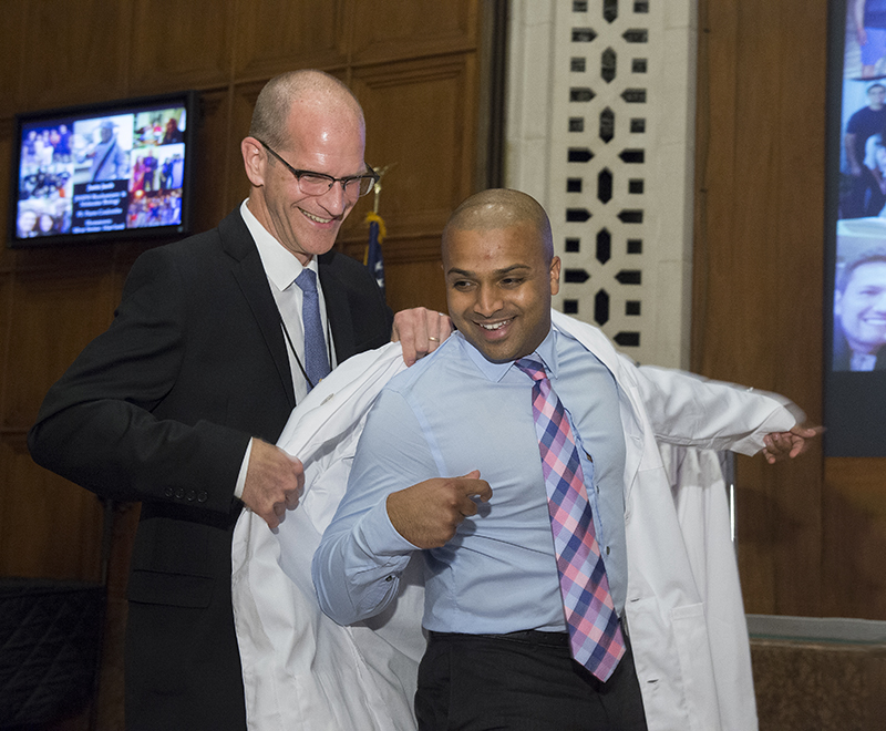 A graduate student receives his white coat.