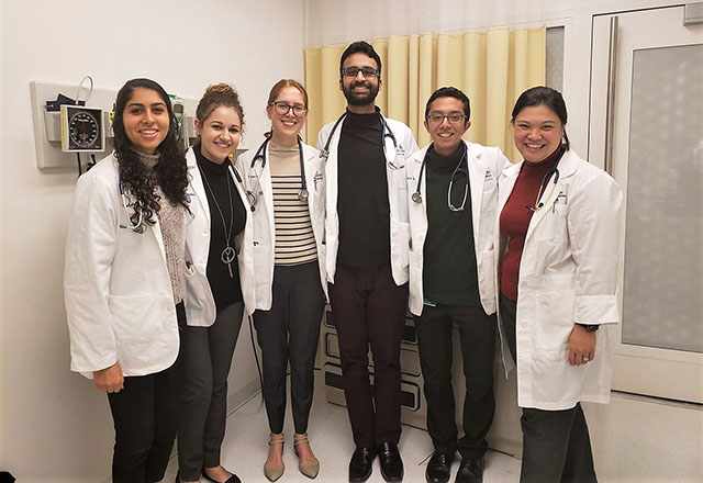 A group of students stand together in white coats.