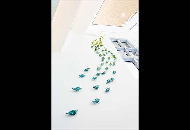 Photograph of Lea de Wit's Cascade of Tranquility, showing teardrop shaped sculptures climbing the wall of a staircase.
