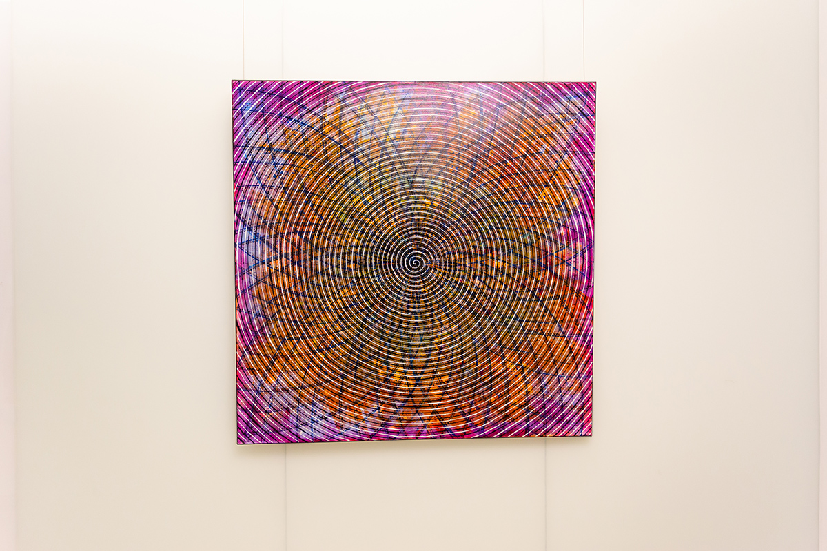 Photograph of Time Information by Shanthi Chandrasekar, shown on canvas are spiraling white lines over black lines arcing from the middle to the outer edges on to of a yellow flower shape on a pink background.