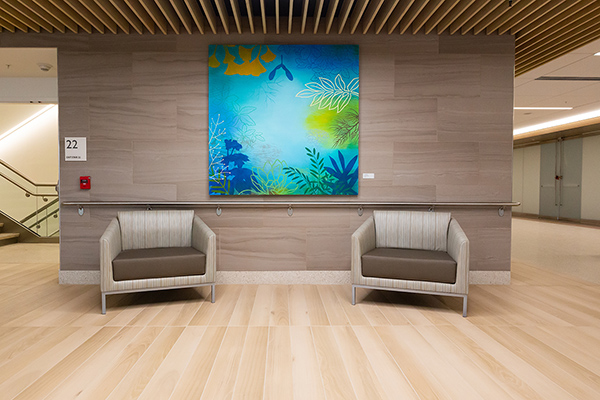 Photograph of Susan Danko's Blue Botanical hanging in a room with an armchair on each side.