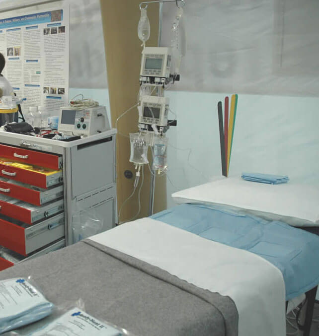 Interior of the emergency tent, showing a patient area with a bed and IV.