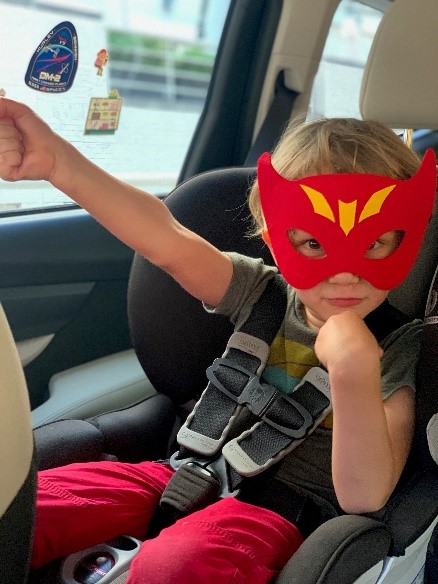 Braden James sitting in a car seat, wearing a red The Flash superhero mask