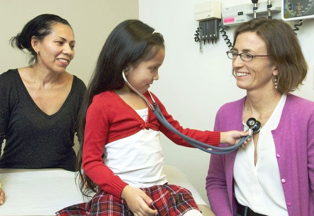 A child uses a stethoscope on a doctor during her wellness exam
